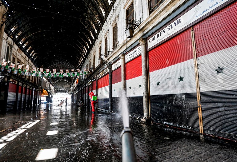  Syrian Red Crescent member sprays disinfectant along an alley of the historic Hamidiyah souk  in Damascus on March 22, 2020. Photo: Louai Beshara/ AFP