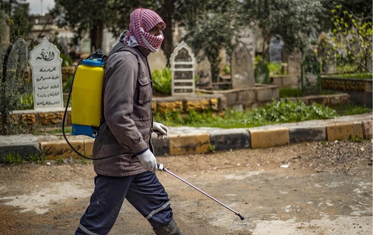A man disinfects a cemetery in the Syrian Kurdish-majority city of Qamishli, March 19, 2020. Photo: Delil Souleiman / AFP