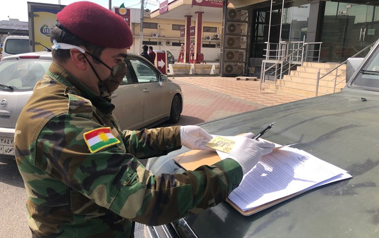 A Zeravani police force member writes up a motorist fine in Erbil on March 24, 2020. Photo: Fazel Hawramy / Rudaw
