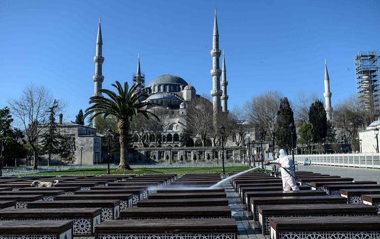 A member of the Fatih Municipality disinfects Istanbul's Sultanahmet square with the Blue Mosque seen in the background on March 21, 2020. Photo: Bulent Kilic/AFP