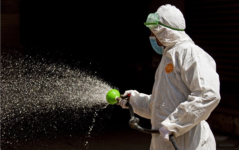 An Iraqi health worker sprays disinfecting liquid in the streets of Basra, March 25, 2020. Photo: Hussein Faleh / AFP