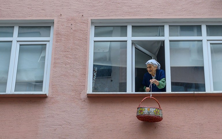 An elderly Turkish woman lowers a basket from her window to receive a delivery of medicine while self-isolating at her home in Istanbul, March 23, 2020. Photo: Bulent Kilic / AFP
