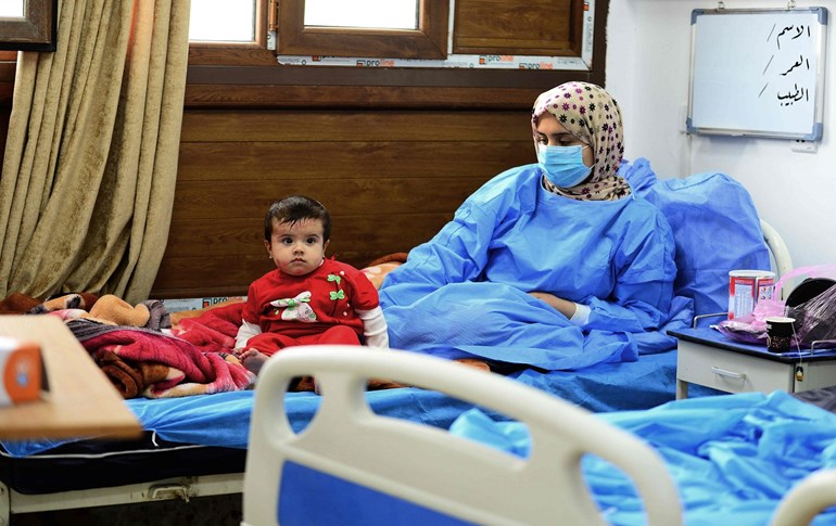  A child sits next to an Iraqi coronavirus patient at a special ward at the Hakim Hospital in Najaf on March 25, 2020. Photo: Haidar Hamdani/AFP