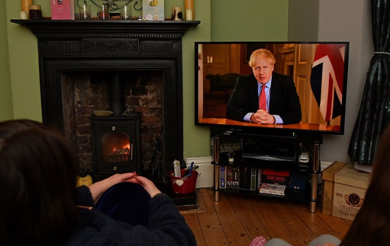 A family listens as Britain’s Prime Minister Boris Johnson makes a televised address to the nation from inside 10 Downing Street in London, March 23, 2020. Photo: Paul Ellis / AFP