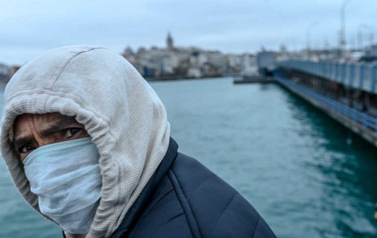A man wearing a protective mask walks along the Galata bridge in central Istanbul on March 26, 2020. Photo: Bulent Kilic/AFP
