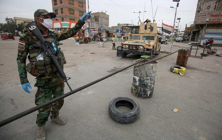 Iraqi soldiers, wearing protective face-masks and gloves, man a checkpoint at the entrance of Baghdad's eastern Sadr City suburb, March 28, 2020. Photo: Ahmad al-Rubaye / AFP