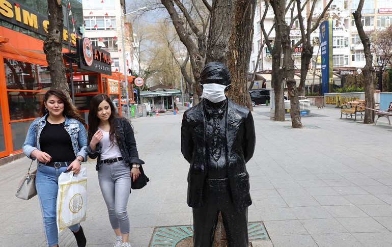 Two ladies pass a statue with a face mask on Yuksel Street in Ankara, April 1, 2020. Photo: Adem Altan / AFP