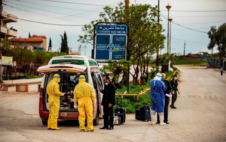 Members of the Kurdish Red Crescent check passengers upon their arrival at the Qamishli airport, April 5, 2020. Photo: Delil Souleiman / AFP