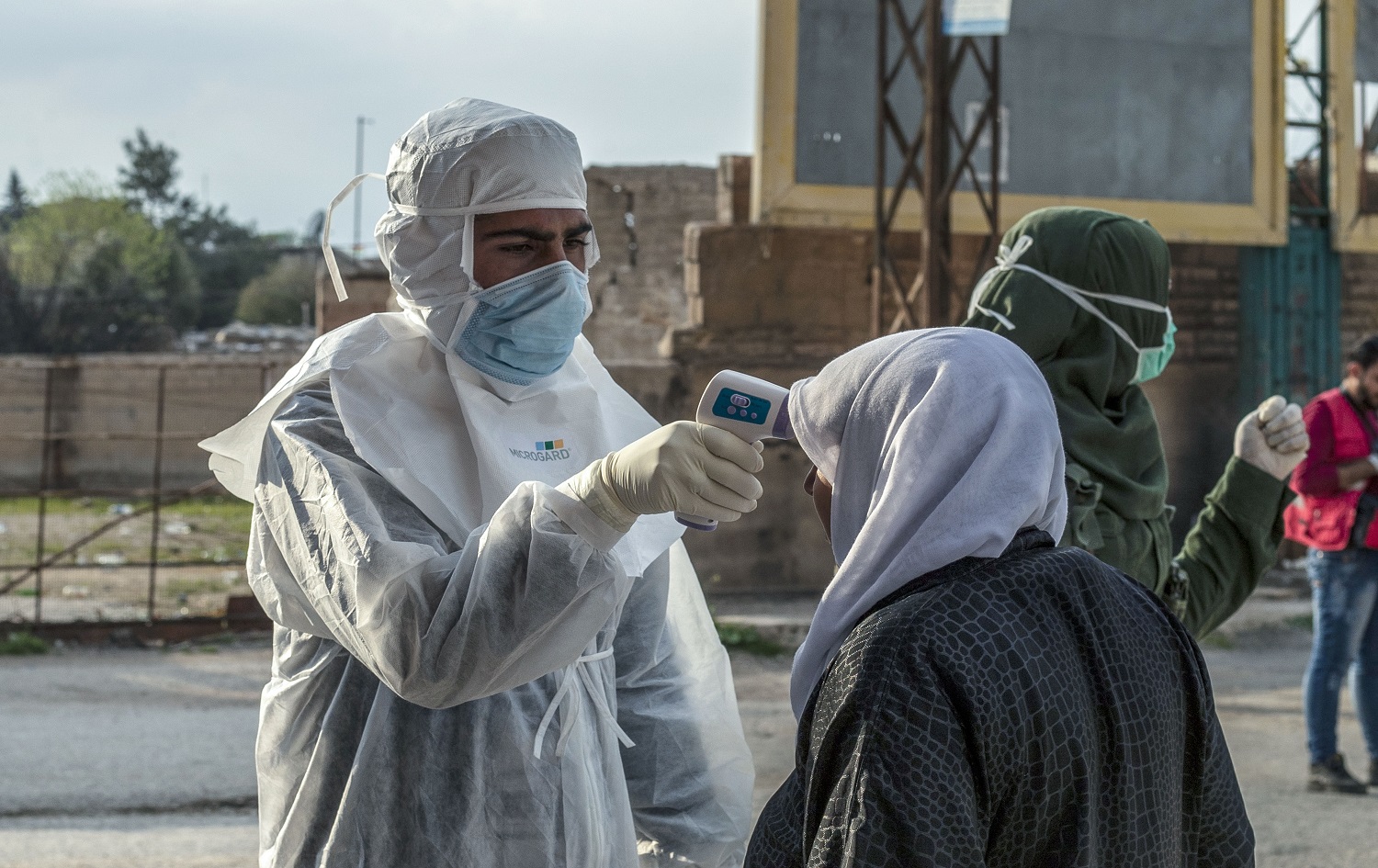 A member of the Kurdish Red Crescent checks the temperature of a passenger upon arrival from Damascus just outside Qamishli on April 7, 2020. Photo: Delil Souleiman / AFP