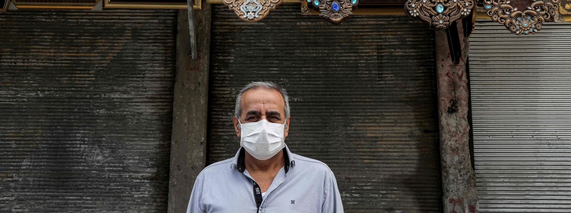   A man wearing a face mask stands outside a closed shop in Erbil on April 16, 2020. Photo: Safin Hamed/AFP   	