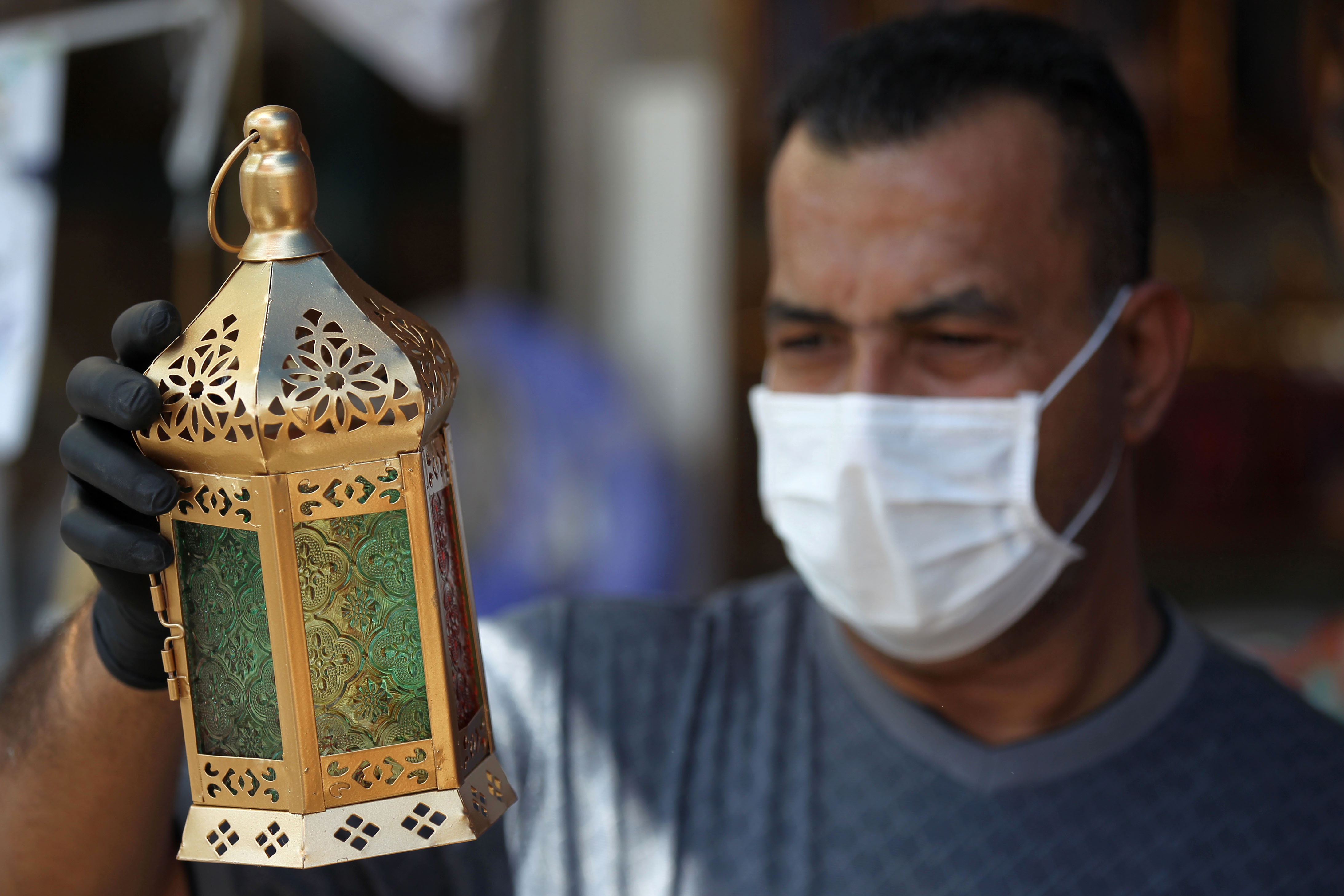 An Iraqi man wearing plastic gloves and a protective mask holds a traditional lantern known in Arabic as "Fanous" at the Shorja market in central Baghdad on April 21, 2020. Photo: Ahmad Al-Rubaye/ AFP