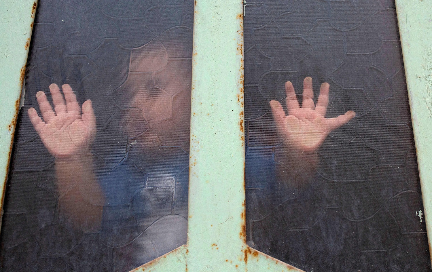 An Iraqi child looks out through a window pane amid confinement due to the COVID-19 pandemic, in the southern city of Basra, April 25, 2020. Photo: Hussein Faleh / AFP