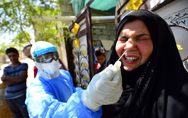 An Iraqi medic takes a nasal swab from a woman in Iraq's central shrine city of Najaf, April 20, 2020. Photo: Haidar Hamdani / AFP 