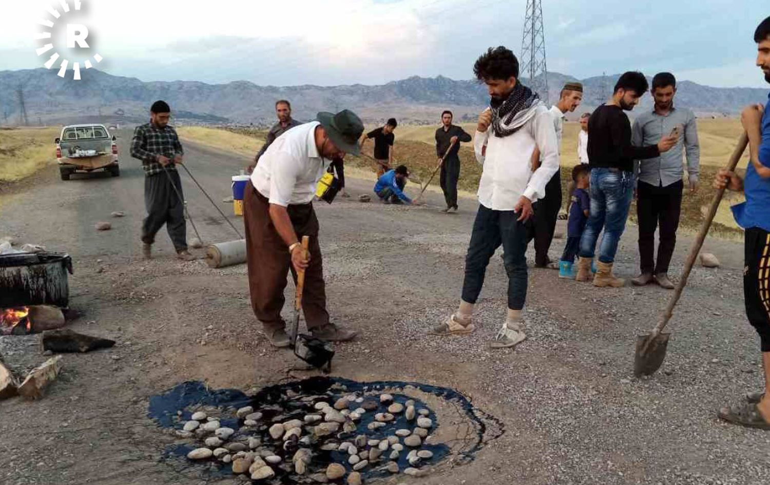 چەند هاونیشتمانییەک چاڵەکانی رێگەی گوندەکەیان قیر دەکەن