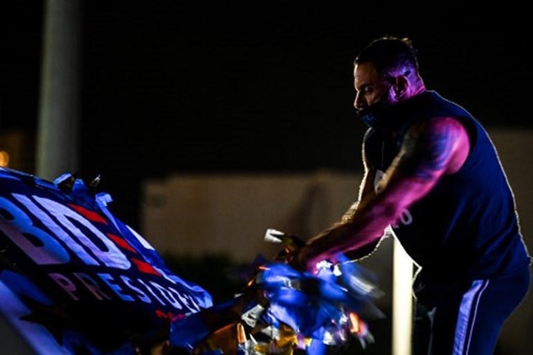 Demetri Zunzunegui romoves the Biden-Harris flag from his car after a watch party in Miami, Florida early on November 4, 2020. CHANDAN KHANNA / AFP