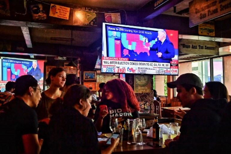 Democrat Party supporters watch the vote count in the US elections in a restaurant in Bangkok on November 4, 2020. Lillian SUWANRUMPHA / AFP
