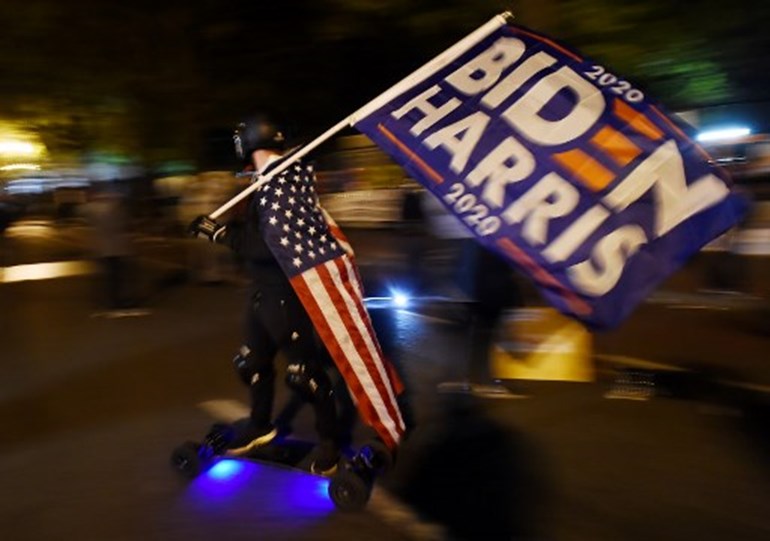 A man waves a Biden-Harris flag as demonstrators gather at Black Lives Matter plaza across from the White House on election night in Washington, DC on November 3, 2020. Olivier DOULIERY / AFP