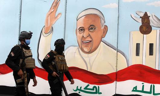 Members of the Iraqi special forces stand guard outside the Syriac Catholic Church of Our Lady of Deliverance, in front of a mural painting welcoming Pope Francis, in Baghdad, on March 4, 2021. Photo: Ahmad al-Rubaye/AFP