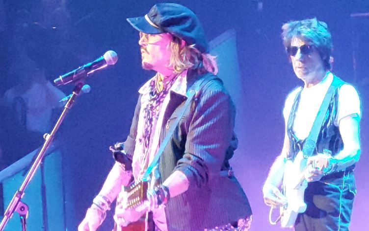 جۆنی دێپ لە کۆنسێرتێکدا گیتار دەژەنێت و گۆرانی دەڵێت