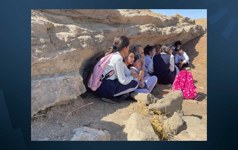 چەند قوتابییەکی کۆیە لەگەڵ مامۆستاکەیان لەترسی تۆپبارانەکانی ئێران پۆلەکانیان جێهێشتووە و لەژێر تاشەبەردێک خۆیان حەشارداوە. وێنە: تۆڕە کۆمەڵایەتییەکان
