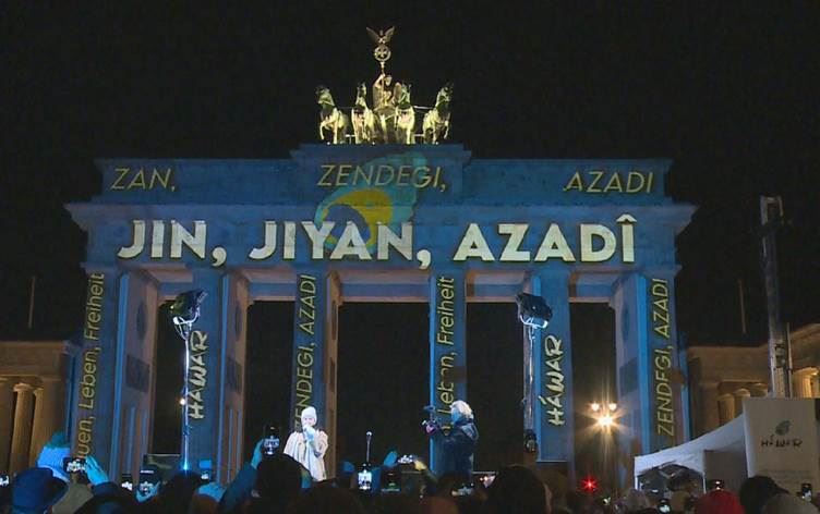 Dirûşma Kurdî “Jin, Jiyan, Azadî” li ser Deriyê Brandenburgê hat nivîsandin