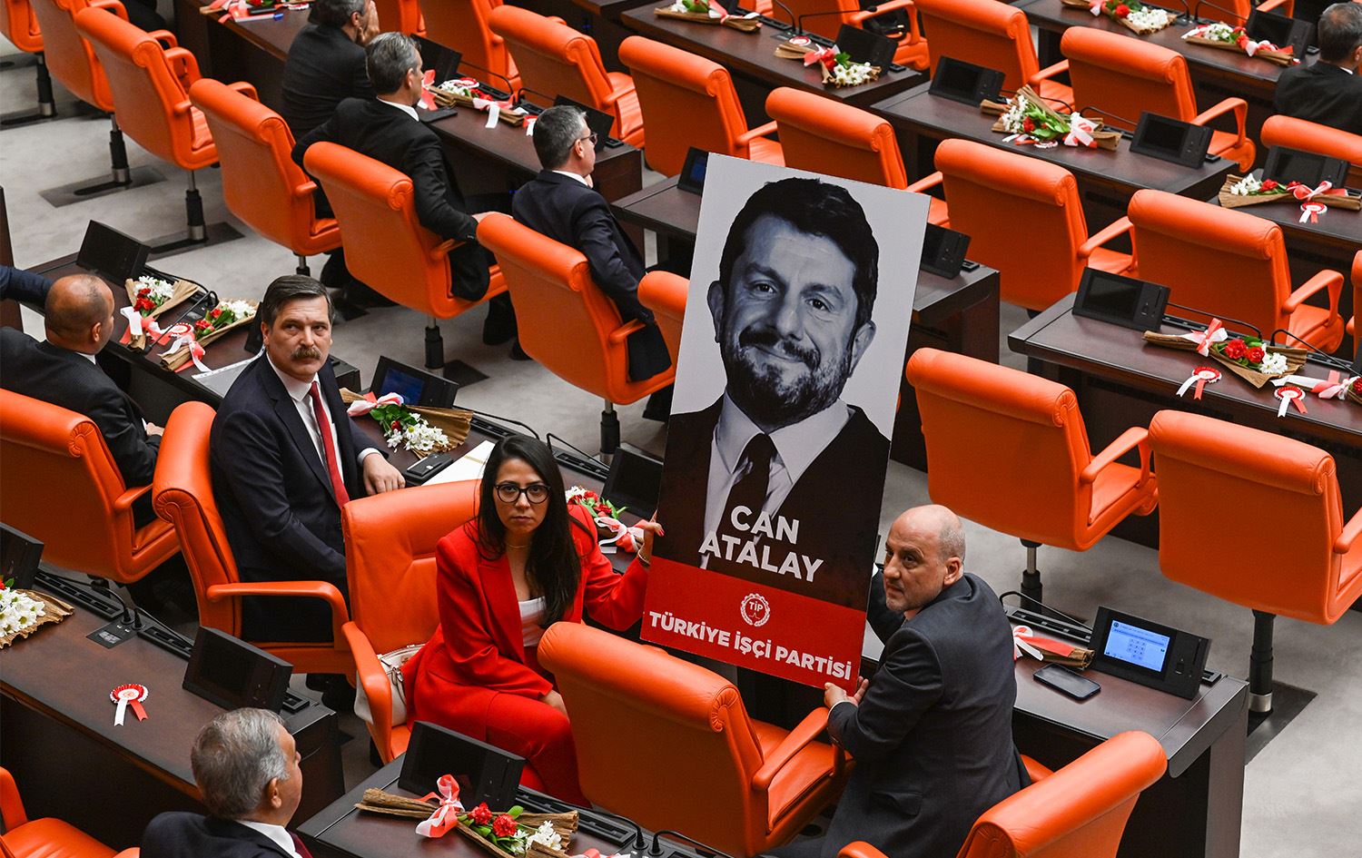 Du parlamenterên Partiya Karkerên Tirkiyê (TÎP) wêneyê Can Atalay ku di hilbijartinên 14ê Gulanê de wek parlamenterê Hatayê yê wê partiyê hat hilbijartin, di civîna parlamentoya Tirkiyê de bilind kirine. Wêne: AA 