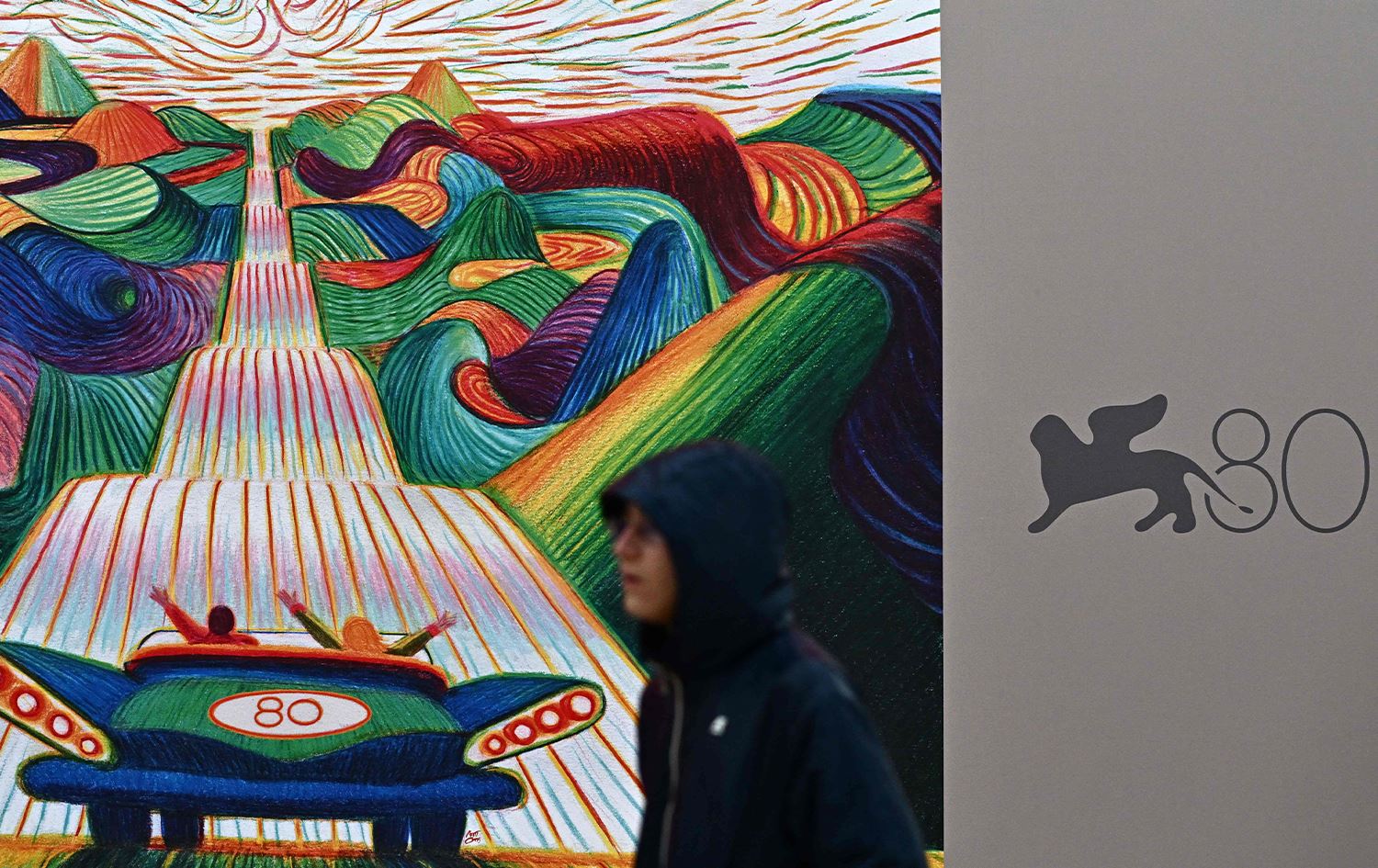 گەنجێک لە بەردەم پۆستەری 80مین فێستیڤاڵی فیلمی ڤێنس تێدەپەڕێت. وێنە؛ AFP