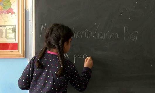 فتاة كوردية تكتب على لوحة (السبورة) باللغة الكوردية
