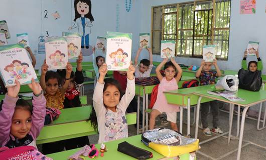 Students hold up Kurdish language books in a class in Rojava. Photo: ANHA/file 