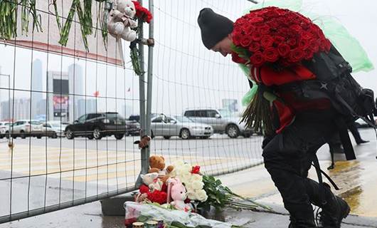 امرأة تضع الزهور على نصب تذكاري مؤقت أمام قاعة مدينة كروكوس عققب الهجوم المسلح