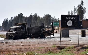 A burnt-out vehicle is seen next to the ISIS group's flag on the outskirts of the Syrian city of Raqqa on June 11, 2017. Photo: AFP
