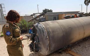 مجندة إسرائيلية تنظر إلى بقايا صاروخ إيراني - AFP