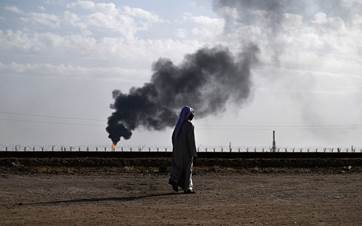 Local resident Hussein Julood walks in front of his house as smoke billows from gas flaring in the nearby Rumaila oil field in Iraq's southern province of Basra, on May 5, 2024. Photo: Hussein Faleh/AFP