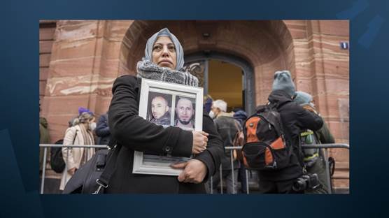 الناشطة السورية ياسمين المشعان عضو رابطة عائلات قيصر تحمل صور ضحايا أمام محكمة في ألمانيا - AFP