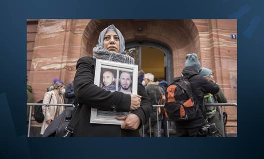 الناشطة السورية ياسمين المشعان عضو رابطة عائلات قيصر تحمل صور ضحايا أمام محكمة في ألمانيا - AFP