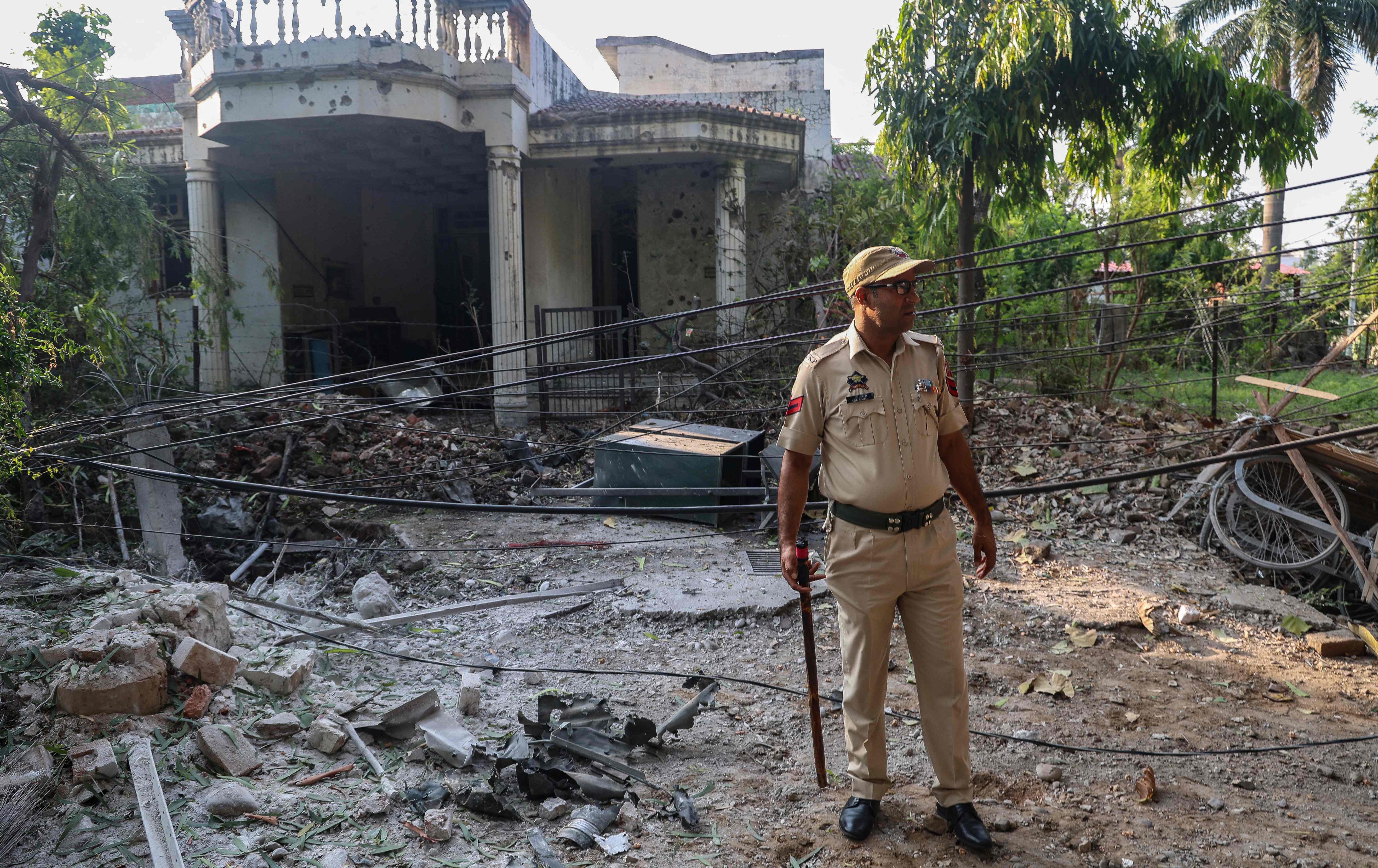 پۆلیسێکی هیندی لە بەردەم خانوویەک وەستاوە کە بە هۆی تۆپبارانی پاکستانەوە زیانی پێگەیشتووە. وێنە: Rakesh BAKSHI / AFP