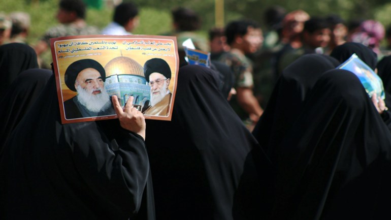 Woman carries poster of Grand Ayatollah Ali al-Sistani (L) and Ayatollah Ali Khamenei (R). Photo: AFP