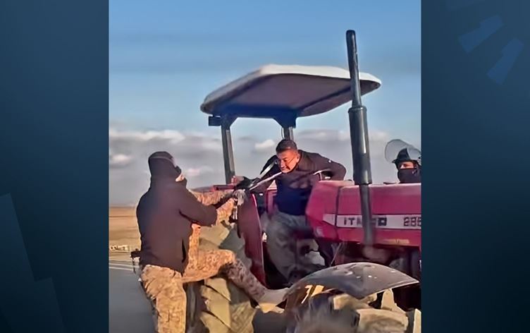 Irak askerinin Kürt çiftçinin puşisinden (atkısından) çekilerek traktörden düşürmeye çalışması