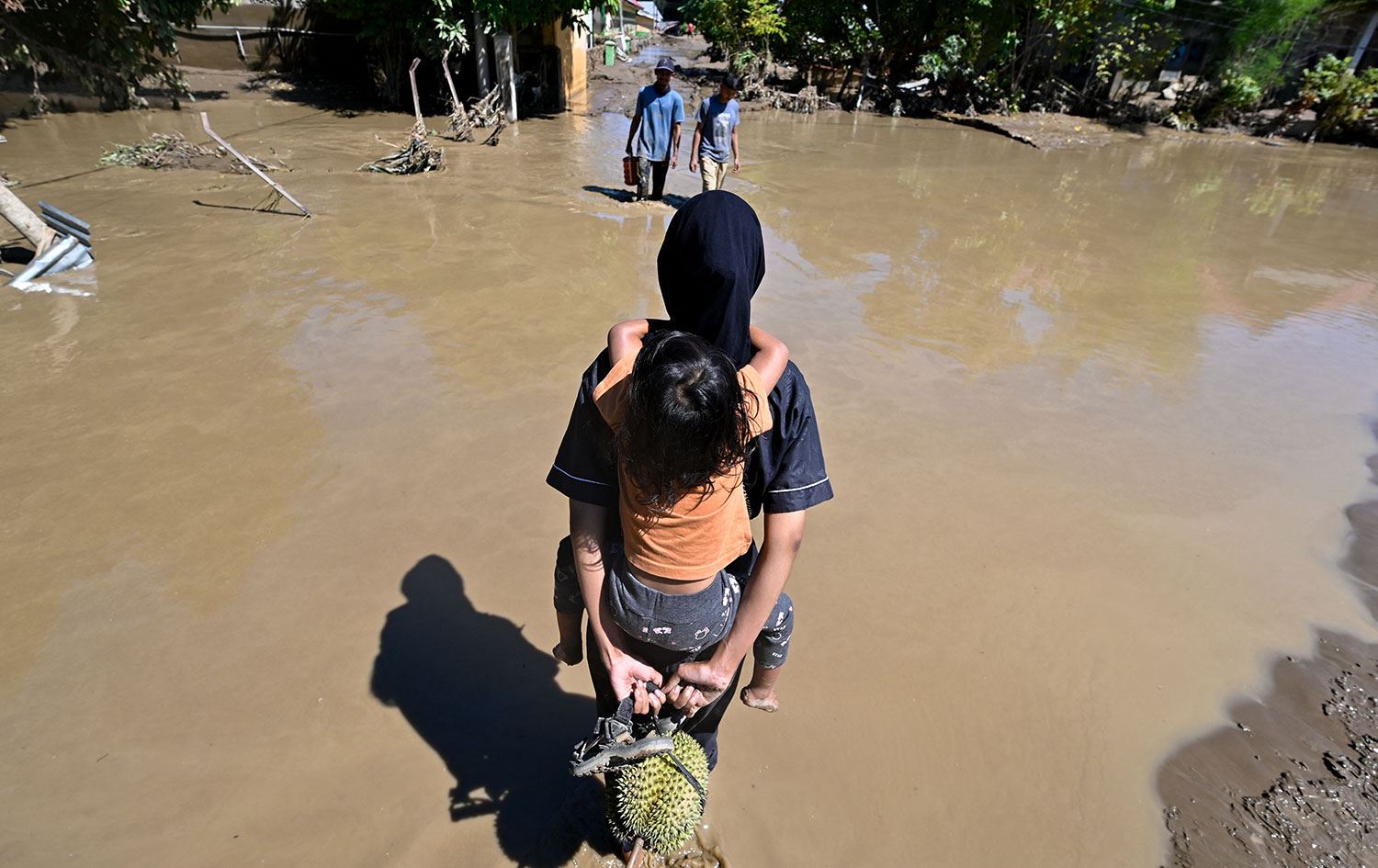 Endonezya'nın Açe eyaletine bağlı Pidie Jaya bölgesindeki Meureudu'da sel baskınına uğramış bir bölgede yürüyen insanlar. / 30 Kasım 2025 / Foto: AFP