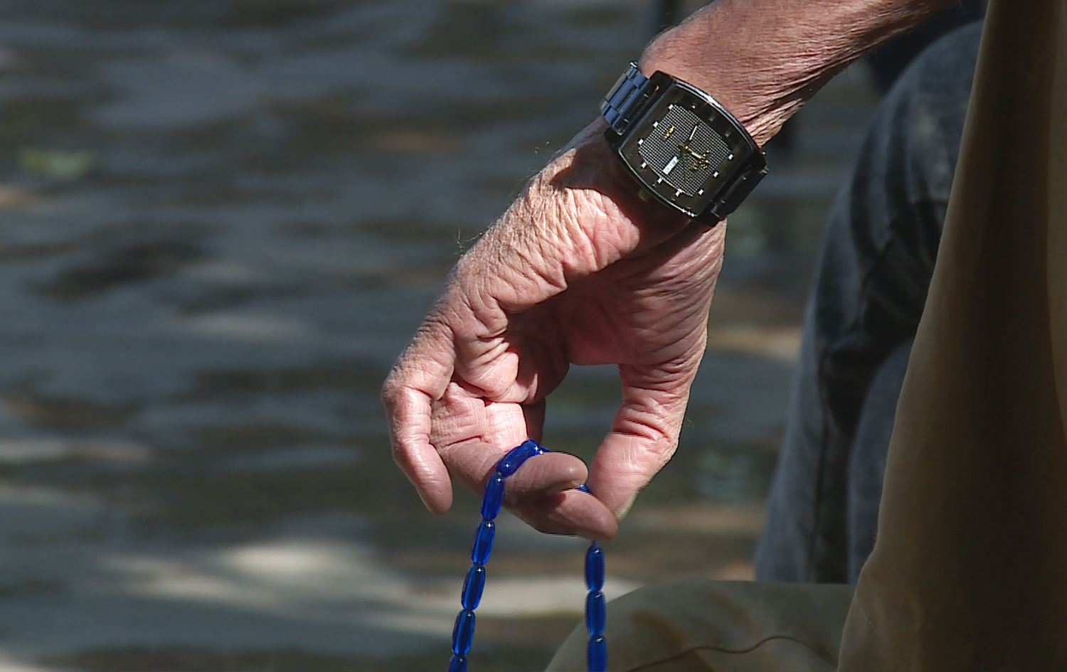 پیاوێکی بەساڵاچوو (کە گرووپێکی مەترسیدارە بۆ نەخۆشییەکە) تەزبیحێکی بەدەستەوەیە.