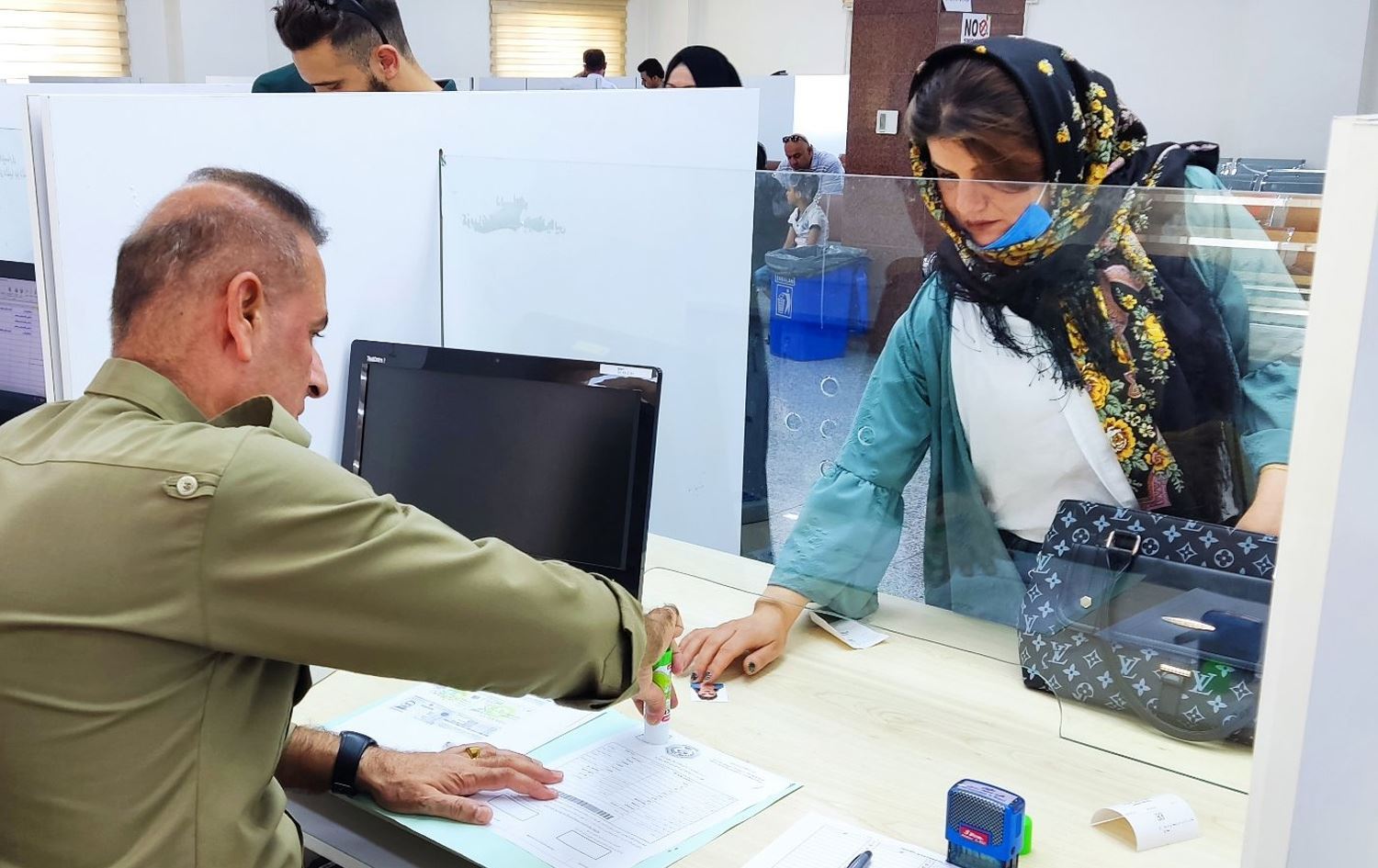 کارمەندێکی پاسپۆرتی سلێمانی پەنجەمۆر بە ژنێک دەکات