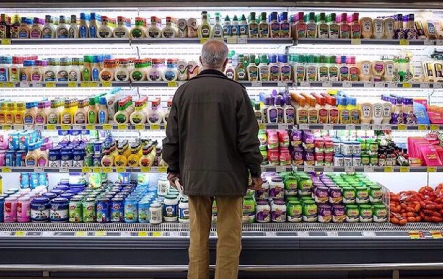 کەسێک لە مارکێتێکی ئێران سەیری بەرهەمە شیرەمەنییەکان دەکات.