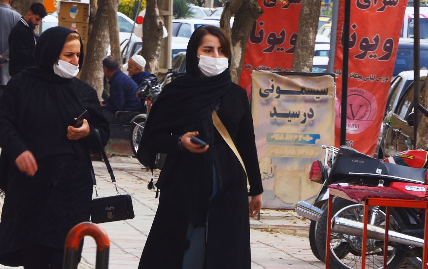 دوو خانم دەمامکیان بەستووە لەنێو بازاڕێکی ئێران. وێنە: رووداو