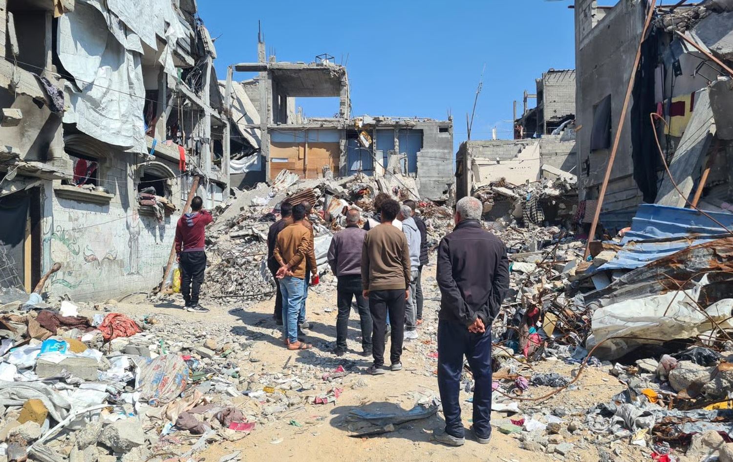 چەند کەسێک لە غەززە سەیری خانووە رووخاوەکانیان دەکەن