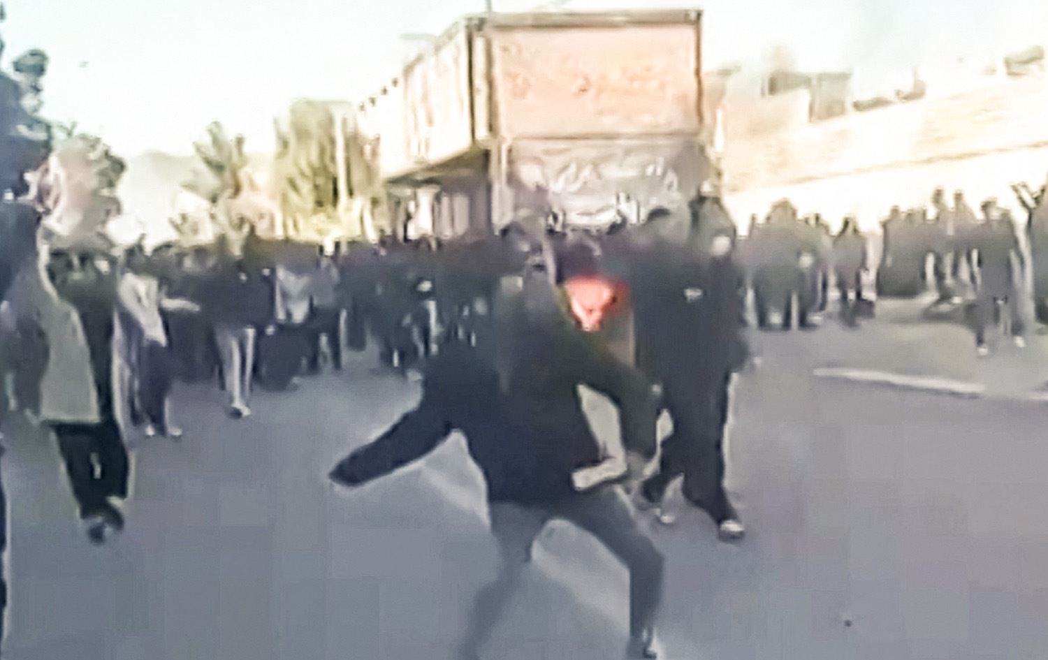 دیمەنێک لە خۆپێشاندانەکەی ئێران، یەکێکیان بەردی بەدەستەوەیە و لە پۆلیسی دەگرێت. وێنە: UGC / AFP