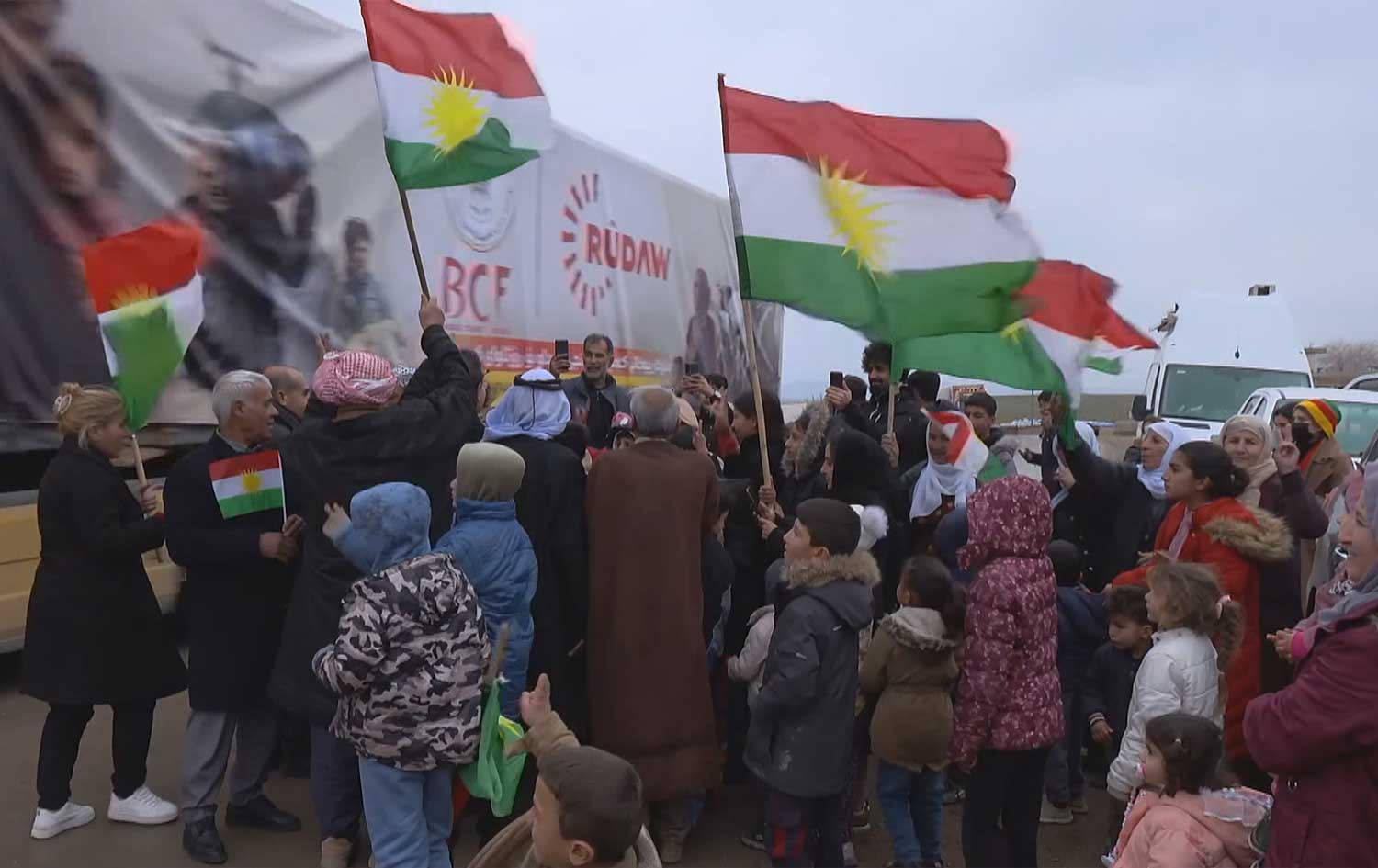 Residents of northeast Syria (Rojava) raise the Kurdistan flag in celebration as Rudaw’s humanitarian aid convoy arrives in the region on January 28, 2026. Photo: Screengrab/Rudaw