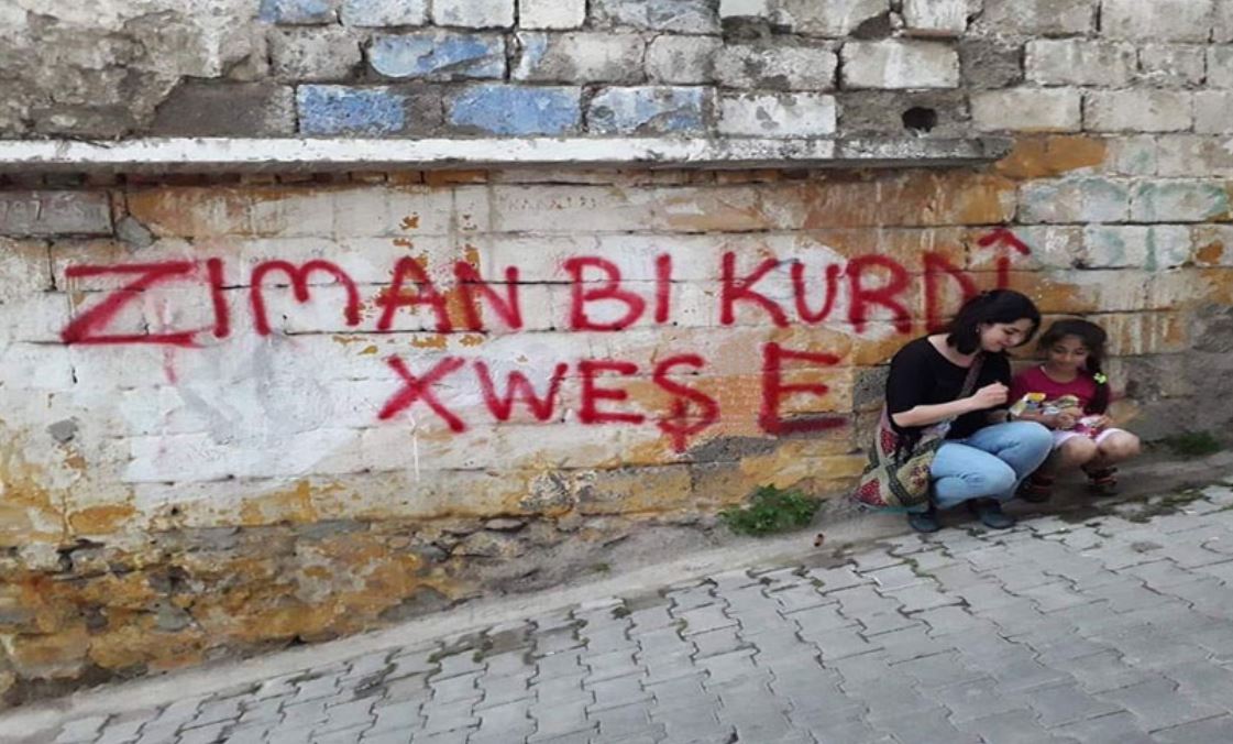 "زمان بە کوردی خۆشە"، لەسەر دیوارێک نووسراوە.