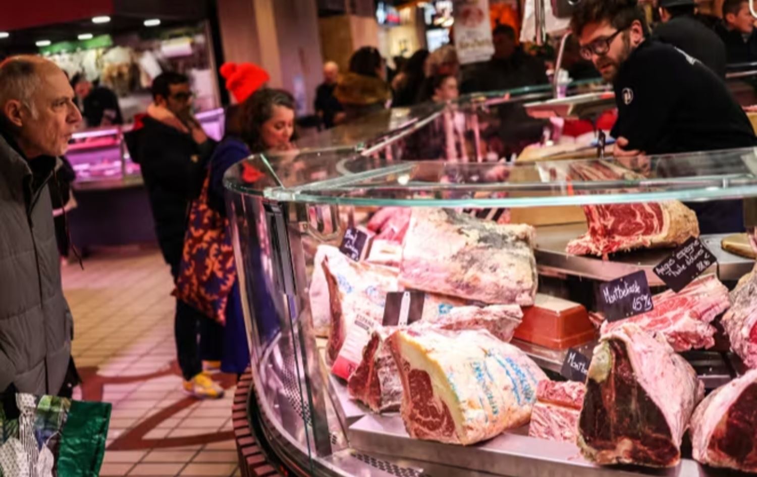 چەند هاووڵاتییەکی فەرەنسا لە گۆشتفرۆشێک سەیری گۆشت دەکەن