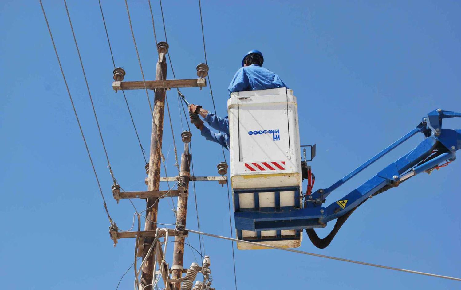 فني يصلح خطاً لنقل الكهرباء