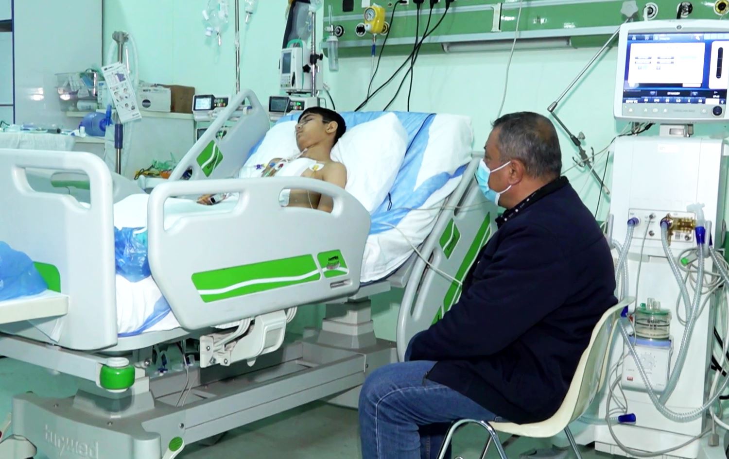 منداڵێک کە نەشتەرگەریی دڵی بۆ کراوە. باوکیشی دانیشتووە و بەدیارییەوەیەتی.